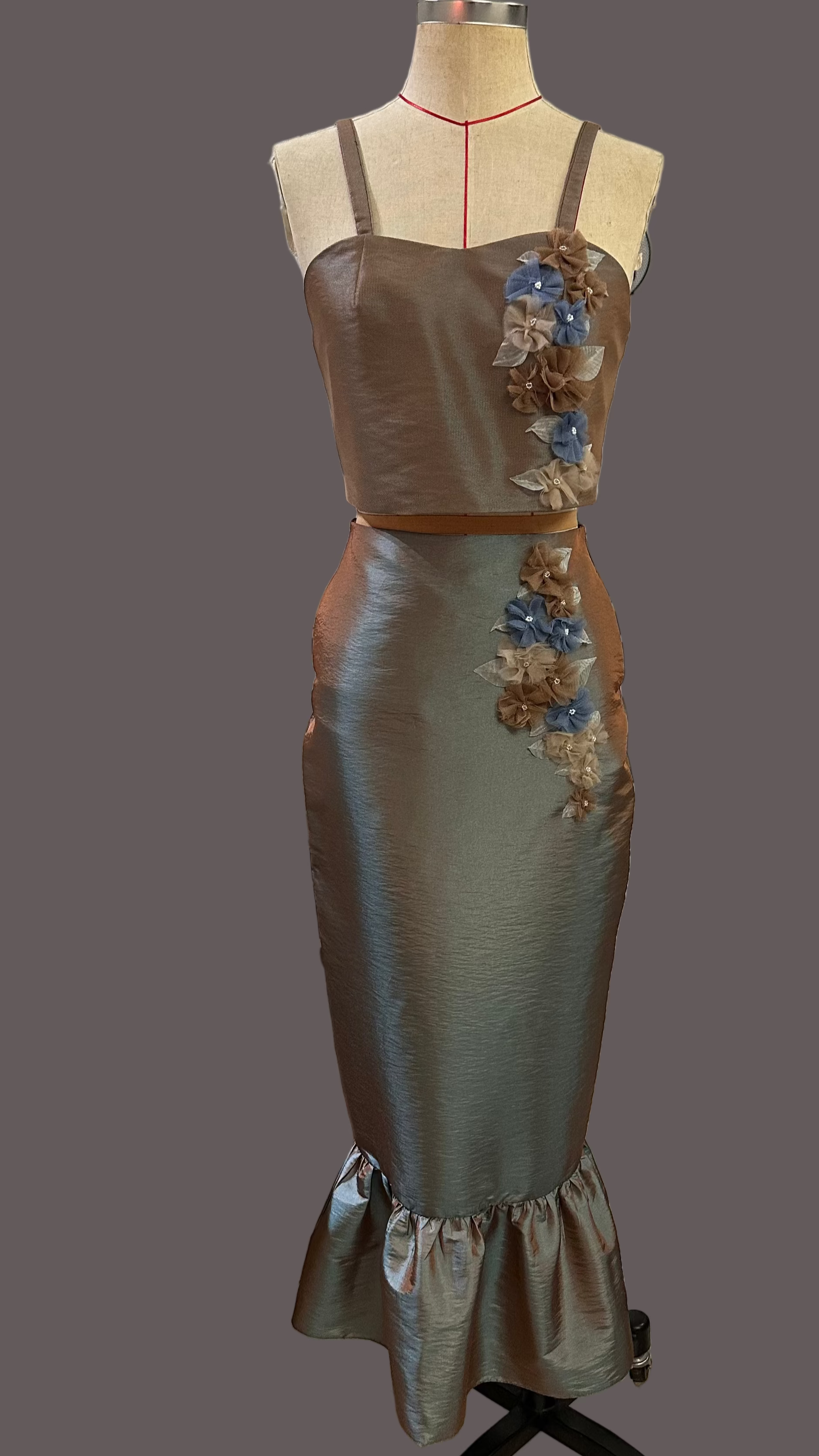 Satin dress with floral embellishments on a mannequin against a gray background